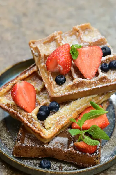 Renkli çan biberlerinin üst görüntüsü. İçi öğütülmüş et, pilav ve karışık sebzelerle doldurulmuş. Seramik bir fırın kabına dizilmiş.. 