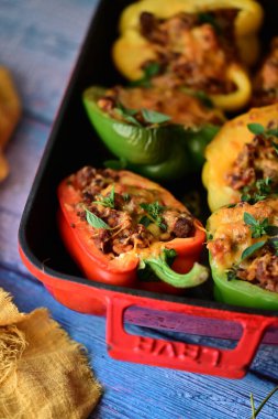 Doldurulmuş biber, et, peynir ve sebzeler, mavi ahşap bir arka planda kızartma tavasında..