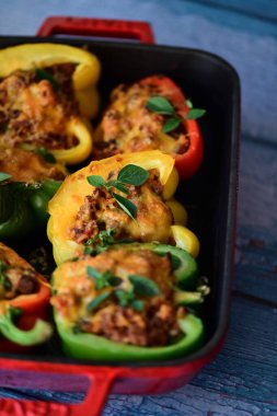 Doldurulmuş biber, et, peynir ve sebzeler, mavi ahşap bir arka planda kızartma tavasında..