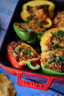 Doldurulmuş biber, et, peynir ve sebzeler, mavi ahşap bir arka planda kızartma tavasında..
