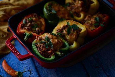 Doldurulmuş biber, et, peynir ve sebzeler, mavi ahşap bir arka planda kızartma tavasında..