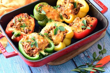 Doldurulmuş biber, et, peynir ve sebzeler, mavi ahşap bir arka planda kızartma tavasında..