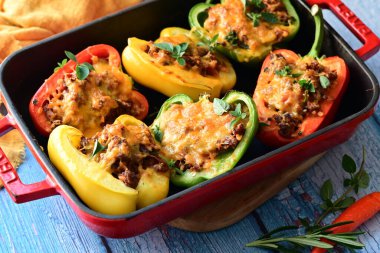 Doldurulmuş biber, et, peynir ve sebzeler, mavi ahşap bir arka planda kızartma tavasında..