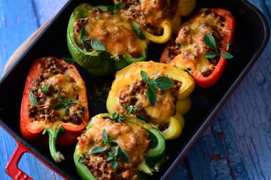 Doldurulmuş biber, et, peynir ve sebzeler, mavi ahşap bir arka planda kızartma tavasında..