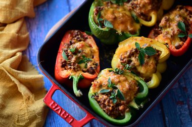 Doldurulmuş biber, et, peynir ve sebzeler, mavi ahşap bir arka planda kızartma tavasında..