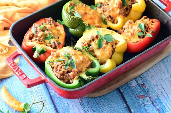 Doldurulmuş biber, et, peynir ve sebzeler, mavi ahşap bir arka planda kızartma tavasında..