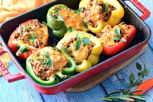 Doldurulmuş biber, et, peynir ve sebzeler, mavi ahşap bir arka planda kızartma tavasında..