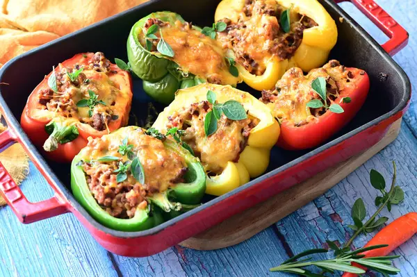 Doldurulmuş biber, et, peynir ve sebzeler, mavi ahşap bir arka planda kızartma tavasında..
