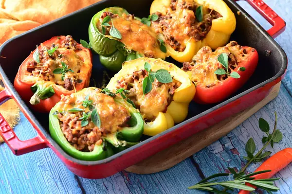 Doldurulmuş biber, et, peynir ve sebzeler, mavi ahşap bir arka planda kızartma tavasında..