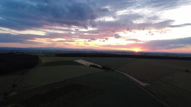 Tarlanın üzerinde buğday tarlalarıyla güzel bir günbatımı görüntüsü.