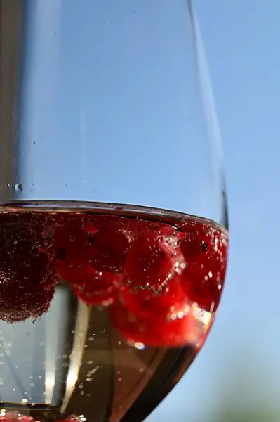 Bir bardak köpüklü beyaz şarap ahududu ve su damlacıklarıyla Taze Ayrıntı ve Baloncuklarla Zarif Yakın plan