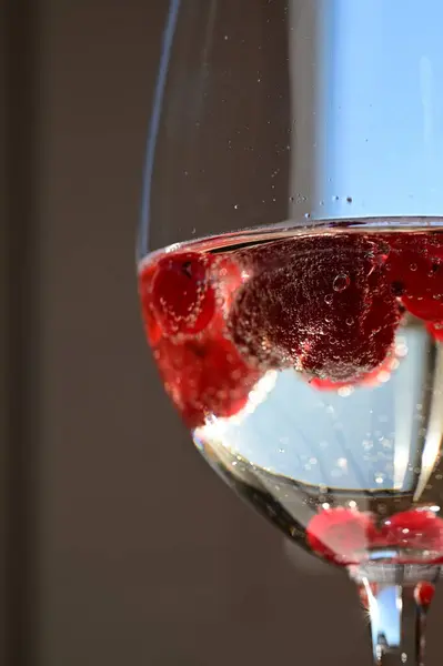 Bir bardak köpüklü beyaz şarap ahududu ve su damlacıklarıyla Taze Ayrıntı ve Baloncuklarla Zarif Yakın plan