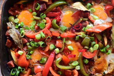 Sebzeli sahanda yumurta, baharat, domates, biber, soğan ve otlar.