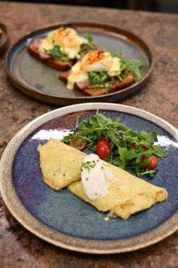 Erimiş peynirle kaplı lezzetli bir omlet, taze domates ve taze otlarla serpiştirilmiş..