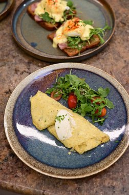 Erimiş peynirle kaplı lezzetli bir omlet, taze domates ve taze otlarla serpiştirilmiş..