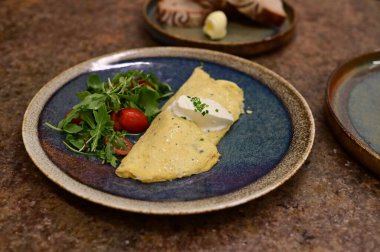 Erimiş peynirle kaplı lezzetli bir omlet, taze domates ve taze otlarla serpiştirilmiş..