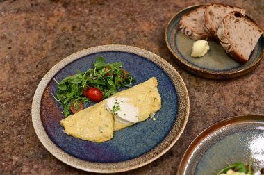 Erimiş peynirle kaplı lezzetli bir omlet, taze domates ve taze otlarla serpiştirilmiş..