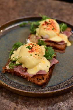 Bu klasik Eggs Benedict tabağında zengin dokular ve canlı renkler yer alıyor. Gurme kahvaltısı, brunch menüleri, yemek blogları ve mutfak promosyonları için ideal..