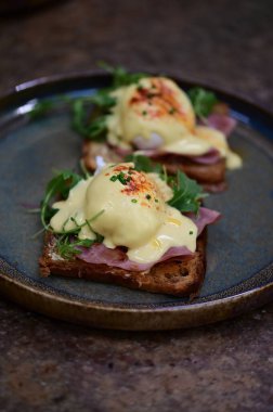 Bu klasik Eggs Benedict tabağında zengin dokular ve canlı renkler yer alıyor. Gurme kahvaltısı, brunch menüleri, yemek blogları ve mutfak promosyonları için ideal..
