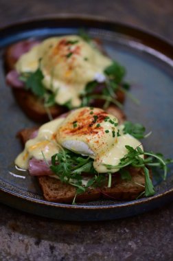 Bu klasik Eggs Benedict tabağında zengin dokular ve canlı renkler yer alıyor. Gurme kahvaltısı, brunch menüleri, yemek blogları ve mutfak promosyonları için ideal..