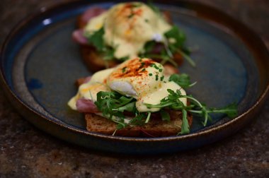 Bu klasik Eggs Benedict tabağında zengin dokular ve canlı renkler yer alıyor. Gurme kahvaltısı, brunch menüleri, yemek blogları ve mutfak promosyonları için ideal..