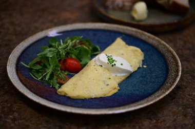 Erimiş peynirle kaplı lezzetli bir omlet, taze domates ve taze otlarla serpiştirilmiş..