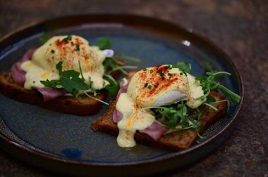 Bu klasik Eggs Benedict tabağında zengin dokular ve canlı renkler yer alıyor. Gurme kahvaltısı, brunch menüleri, yemek blogları ve mutfak promosyonları için ideal..