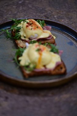 Bu klasik Eggs Benedict tabağında zengin dokular ve canlı renkler yer alıyor. Gurme kahvaltısı, brunch menüleri, yemek blogları ve mutfak promosyonları için ideal..