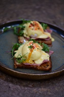 Bu klasik Eggs Benedict tabağında zengin dokular ve canlı renkler yer alıyor. Gurme kahvaltısı, brunch menüleri, yemek blogları ve mutfak promosyonları için ideal..