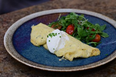 Ev yapımı omlet, taze yeşil yapraklı salata ve vişneli domatesle servis edilir..