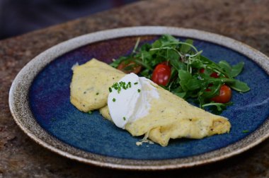 Ev yapımı omlet, taze yeşil yapraklı salata ve vişneli domatesle servis edilir..