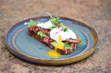 Yumurtalı sandviç, pastırma, ekmek, tost ve krem peynirli ahşap arka planda.