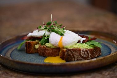 Kavrulmuş yumurtalı avokado tostu, pastırma ve mikroyeşillik gurmesi. Yakın plan kahvaltı.