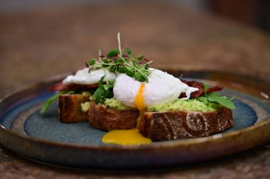 Kavrulmuş yumurtalı avokado tostu, pastırma ve mikroyeşillik gurmesi. Yakın plan kahvaltı.