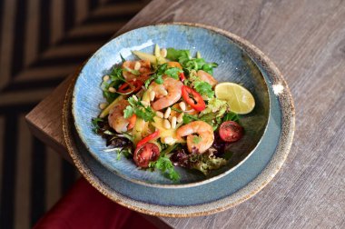 Domatesli lezzetli karidesler ve beyaz tabakta zeytinler.