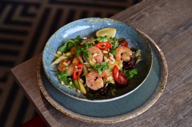 Karidesli salata, avokado ve siyah arka planda domates.