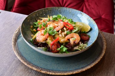 Taze sebzeli ve karidesli baharatlı Tayland salatası. Çok güzel tabaklar ve canlı bir restoran ortamında servis ediliyor. Biber, bitki, limon ve deniz ürünlerini birleştiren renkli, egzotik bir yemek otantik Tayland mutfağı ve sağlıklı beslenmenin mükemmel bir örneğidir..