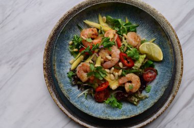 Taze sebzeli ve karidesli baharatlı Tayland salatası. Çok güzel tabaklar ve canlı bir restoran ortamında servis ediliyor. Biber, bitki, limon ve deniz ürünlerini birleştiren renkli, egzotik bir yemek otantik Tayland mutfağı ve sağlıklı beslenmenin mükemmel bir örneğidir..