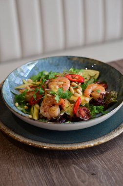 Taze sebzeli ve karidesli baharatlı Tayland salatası. Çok güzel tabaklar ve canlı bir restoran ortamında servis ediliyor. Biber, bitki, limon ve deniz ürünlerini birleştiren renkli, egzotik bir yemek otantik Tayland mutfağı ve sağlıklı beslenmenin mükemmel bir örneğidir..
