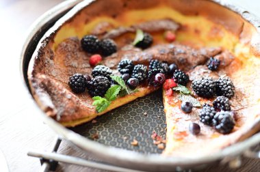 Siyah tabakta ev yapımı yabanmersinli turta pudra şekerli ve tahta kaşıklı.