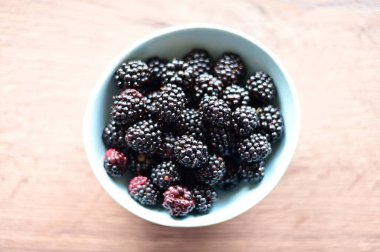 Tahta masada taze böğürtlenli kase, düz yatıyordu. Metin için boşluk