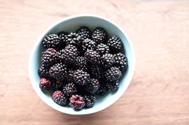 Beyaz arka planda cam bir kasede böğürtlen.