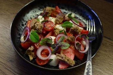 Olgun domatesler, kremalı mozzarella peyniri ve canlı fesleğen yapraklarından oluşan taze bir Caprese salatasının yakın çekimi..