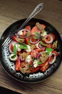 Olgun domatesler, kremalı mozzarella peyniri ve canlı fesleğen yapraklarından oluşan taze bir Caprese salatasının yakın çekimi..