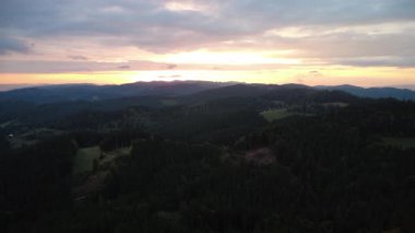 a low angle shot of a beautiful sunset with a forest and mountains