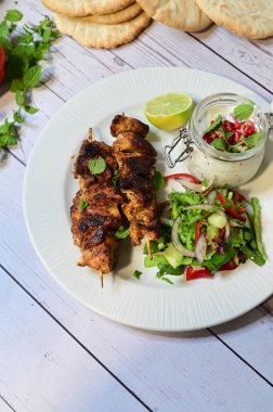 grilled chicken kebab with fresh vegetable salad and pita bread