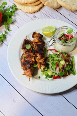 kebab with grilled vegetables and salad on plate.