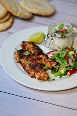 delicious grilled chicken with vegetables and salad on white plate.