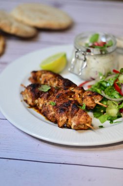 chicken breast with lemon and salad on white plate.
