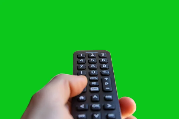 Hand holding a tv remote control isolated on a green screen background for chroma key cut out.